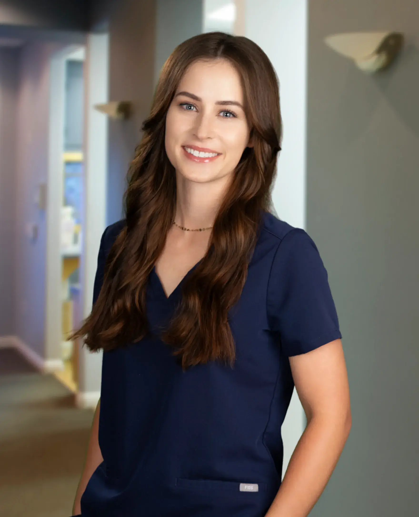 A woman in a navy uniform smiling in a hallway.